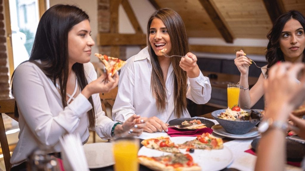 Παρέα 3 γυναικών τρώνε και χαμογελούν