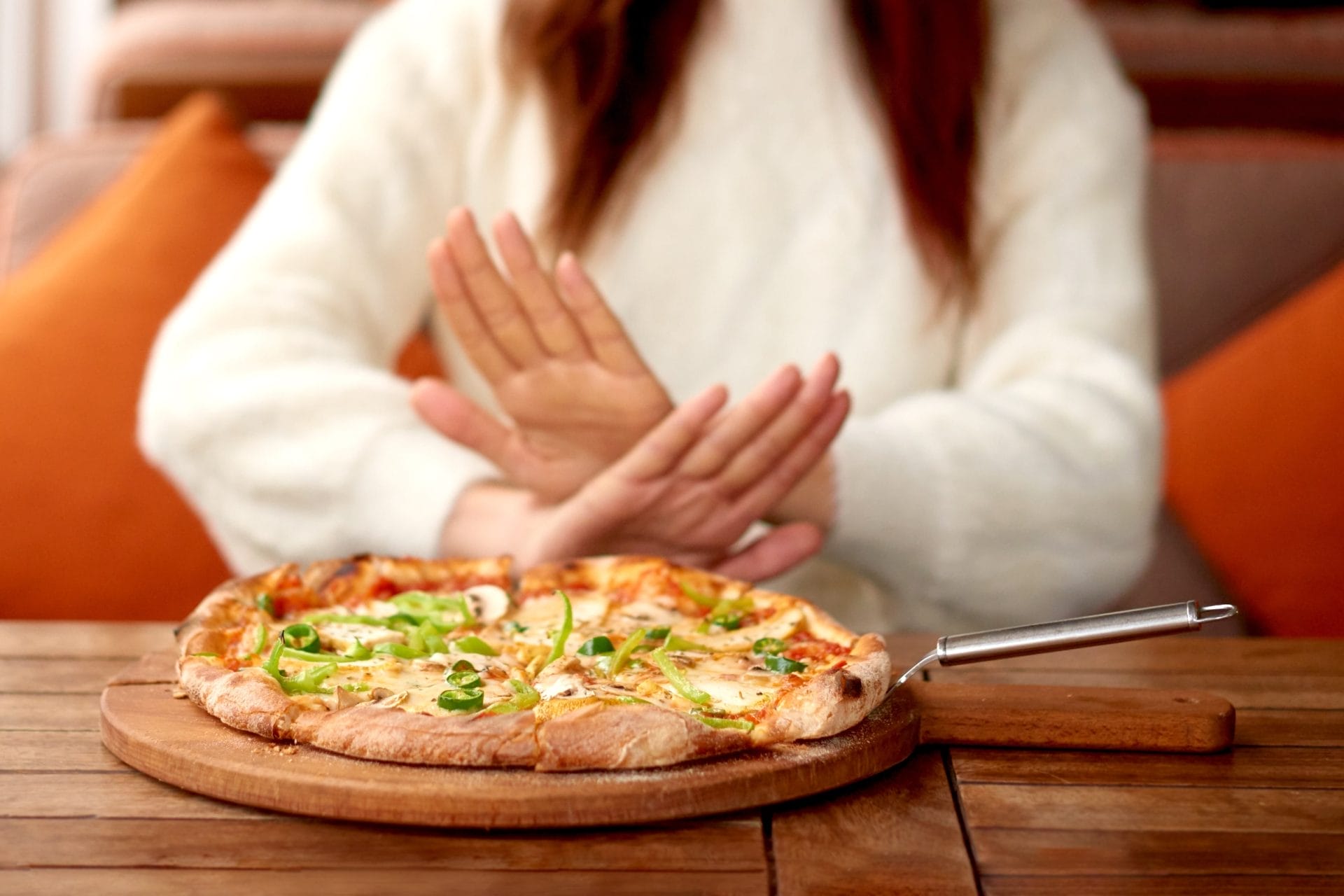 Γυνακεία χέρια αρνούνται πίτσα πάνω σε ξύλινο τραπέζι